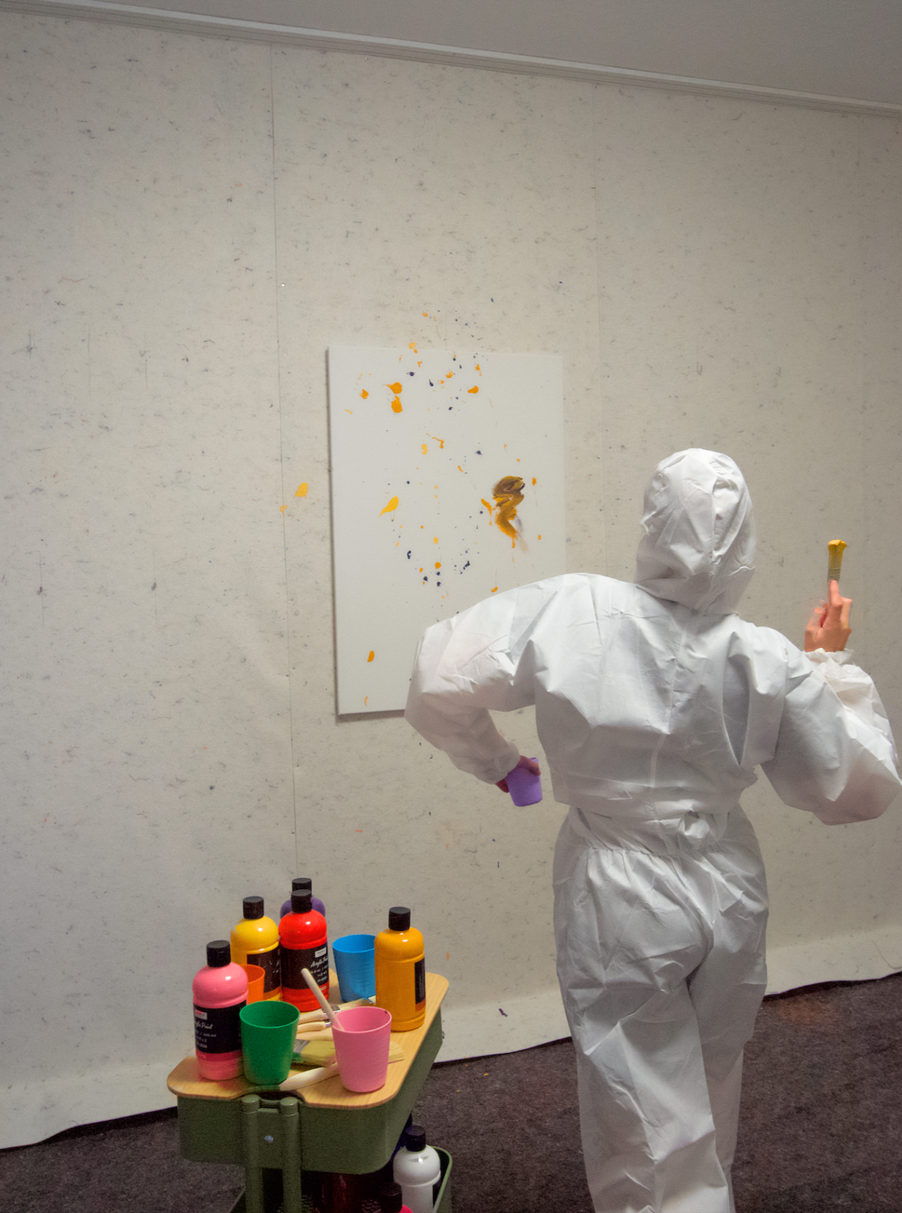 Teilnehmer in Schutzanzug beim Action Painting mit Farbe